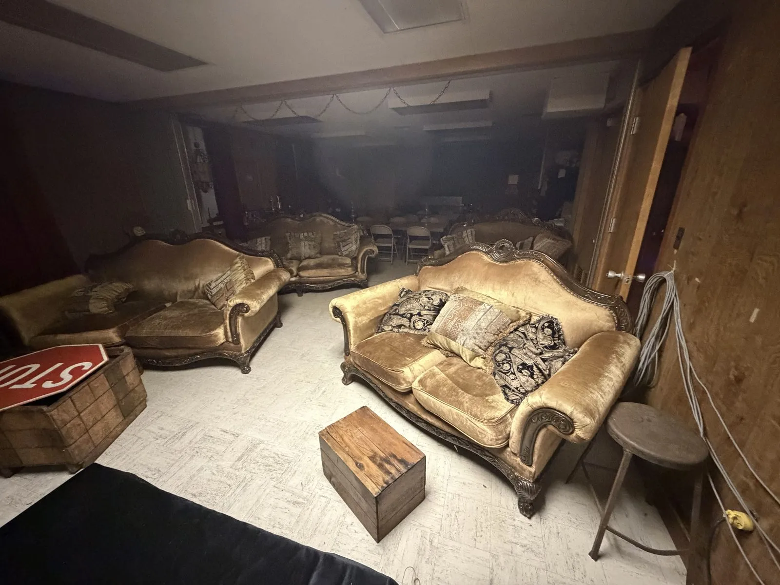 Gold velvet Victorian sofas with carved wooden frames and brocade pillows in a dark lounge
